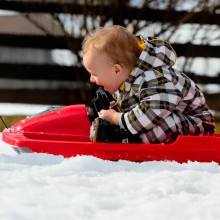 kindje op slee op een kindvriendelijk vakantieadresje met kleine kinderen kinderopvang Jonge Gezinnenweek wintersport in de Berghut Rauris Oostenrijk sneeuw